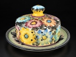 FAIANÇA, uma (1) queijeira confeccionada em faiança vitrificada na tonalidade branca, decorado por flores e folhagens em policromia com filetes na cor preta, apresenta sinais de craquele e prato bicado, medindo 14x26cm.