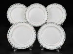 PORCELANA REAL, cinco (5) pratos rasos confeccionados em porcelana na tonalidade branca, decorada por guirlanda floral em policromia e filetes em ouro, medindo 23,5cm. Falhas na douração e pintura, 2 com sinais de craquele. medindo 23,5cm.
