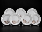 PORCELANA SCHMIDT, sete (7) pratos para sobremesa confeccionados em porcelana nacional na tonalidade branca, decorada por flores e folhagens em policromia, elementos em relevo na pasta e borda filetada em prata, medindo 19,5cm. Leves falhas na prateação.