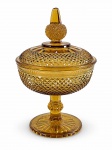 VIDRO, uma (1) compoteira confeccionada em vidro na tonalidade âmbar com moldagem em bico de jaca, haste e pega da tampa com gomo, apoiada sobre base circular com fundo estrelado, medindo 23,5x15cm.