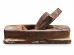 FERRAMENTA, uma (1) plaina confeccionada em madeira escura, acompanha lâmina com sinais de oxidação, peça com sinais de uso, medindo 11x22,5x6cm.
