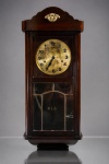 RELÓGIO, um (1) relógio de parede carrilhão, marca JUNGHANS, com mecanismo mecânico de corda, mostrador circular em metal dourado com algarismos arábicos e ponteiros escuros. Caixa em madeira de tonalidade escura, com arremate superior recortado e aplique ornamental em metal dourado, porta frontal envidraçada em bisote com detalhes recortados. Apresenta desgastes no mostrador, marcas do tempo e avaria no vidro. Funcionamento não testado e sem garantia, medindo 80x33,5x17cm.