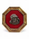 ARTE SACRA, um (1) quadro com imagem em alto-relevo representando JESUS CRISTO, confeccionada em bronze, aplicada sobre fundo em veludo vermelho, emoldurada em moldura oitavada de madeira com patina dourada e acabamento perolado, medindo 33,5cm.