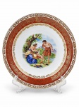 PORCELANA DE BAVARIA, um (1) prato decorativo confeccionado em porcelana alemã na tonalidade branca, decorado por cena idílica em policromia, espessa faixa na tonalidade vermelha com guirlanda floral em vasta douração, medindo 26cm de diâmetro.