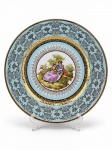 PORCELANA PD 541, um (1) medalhão confeccionado em porcelana na tonalidade branca, ricamente decorada por cena galante em policromia, ricamente adornada por guirlanda floral e vegetalista em vasta douração sobre fundo azul, borda filetada a ouro com falhas na douração, medindo 32cm de diâmetro.