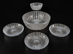 CRISTAIS, conjunto com cinco (5) peças confeccionadas em cristal translucido com lapidação de caneluras e serrilhados em baixo relevo, sendo: A) 1 saladeira, medindo 7,5x22cm, B) 3 pratos para sobremesa, medindo 15,5cm e C) 1 bowl, medindo 5,5x12cm com leve bicado.