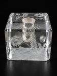 CRISTAL, um (1) castiçal confeccionado em bloco de cristal translúcido com lapidação de elementos florais e vegetalistas em baixo relevo, apresentando bicados, medindo 5,5x8x8cm.