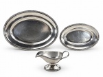 METAL PRATEADO, lote com três (3) peças confeccionadas em metal espessurado a prata da manufatura WOLFF, bordas cinzeladas em caneluras, fitas cruzadas e rosinhas, sendo: A) 2 travessas ovais, medindo 42x30cm e 31x21cm e B) 1 molheira, medindo 10x19x8,5cm. Peças com sinais de uso, vide foto.