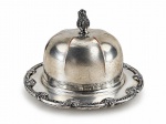 METAL PRATEADO, uma (1) manteigueira confeccionada em metal espessurado a prata SHEFFIELD ARGENTINO, cinzelado em perolados e elementos vegetalistas, tampa em caneluras e pega da tampa no feitio de pinha, apresenta falhas na prateação, medindo 10,5x17cm.