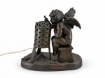 Aristide de Ranieri (Itália,1865-1929), " Amour Frileux", um (1) grupo escultórico e luminária, de petit bronze patinado, representando "cupido se aquecendo" de um amor frio. Placa com inscrições. Presença de selo de fundição. Med. 23 x 26 x 14 de profundidade. Marcas e desgaste do tempo e de uso.