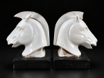 PORCELANA, par (2) de serres livres confeccionados em porcelana na tonalidade branca representando cabeças de cavalo, apoiada sobre base quadrangular na tonalidade preta, ambos bicados e com falhas na douração, medindo 17x14x10cm.