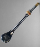 METAL PRATEADO, uma (1) bomba para chimarrão confeccionada em metal prateado, botão de rosa em folhagens com faixa dourada, incrustação de pedra vermelha, sinais de uso, medindo 19cm.