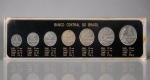 NUMISMÁTICA, coleção comemorativa do BANCO CENTRAL DO BRASIL, composta por sete (7) moedas brasileiras do ano de 1967, pertencentes à primeira série monetária do Cruzeiro Novo, sendo: 1, 2, 5, 10, 20 e 50 centavos e 1 cruzeiro, confeccionadas em diferentes ligas metálicas, incluindo aço inoxidável, cuproníquel e níquel. Acondicionadas em estojo expositor retangular de acrílico transparente, com fundo preto, inscrições BANCO CENTRAL DO BRASIL e especificações individuais de diâmetro, espessura, composição e peso de cada moeda. Conjunto de interesse histórico e numismático, apresentando marcas do tempo no estojo, medindo 5,5x24cm.