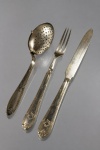 METAL PRATEADO, lote com três (3) peças confeccionadas em metal espessurado a prata, sendo: A) MAPPIN&WEBB, 1 garfo e 1 faca para frutas, cabo cinzelado em caneluras, fitas cruzadas e folhagens e gravação THE BLUE STAR LINE (companhia de navegação britânica Blue Star Line, fundada em 1911) e B) 1 colher coador de chá com cabo cinzelado em estilo art noveau com caneluras e elementos geométricos.
