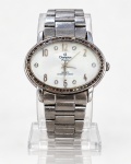 RELÓGIO, um (1) relógio de pulso CHAMPION PASSION, modelo feminino, mecanismo a quartzo (QUARTZ), apresentando caixa oval em metal prateado, mostrador em tom branco perolizado, com algarismos arábicos e marcadores de horas com aplicações de pedras sintéticas brilhantes. Bisel ornamentado com pequenas pedras de strass, apresentando perdas e desgastes. Pulseira metálica prateada, articulada, com fecho dobrável. Fundo em aço inoxidável, gravado com a marca CHAMPION PASSION, referência CV28795 e indicação de resistência à água de 3 ATM. Peça apresentando riscos, oxidação, manchas e marcas acentuadas de uso e do tempo. Funcionamento não testado. No estado, medindo 3x4cm.
