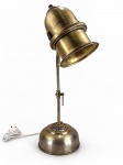 LUMINÁRIA, uma (1) luminária de mesa para uma lâmpada confeccionado em metal dourado, haste cilíndrica com cúpula no feitio de sino articuável com selo ALADDIN MADE IN USA, base circular escalonada com cinzelado vegetalistam assinada, medindo 50,5cm de altura.