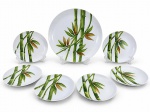 PORCELANAS, conjunto para bolo com sete (7) peças confeccionadas em porcelana na tonalidade branca, decorada por bambuzais e folhagens em policromia, sendo: A) 1 prato para bolo, medindo 32cm de diâmetro e B) 6 pratos para sobremesa, medindo 19cm.