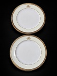 PORCELANA CAULDON, par (2) de pratos decorativos confeccionados em porcelana inglesa na tonalidade branca, espessa faixa na cor creme, borda filetada em ouro com gregas pretas, monograma em reserva possivelmente Joaquim José Moreira Lima Júnior, Visconde de Moreira Lima, posteriormente elevado a Conde de Moreira Lima, em 1887, leves falhas na douração, medindo 22cm.