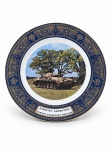 PORCELANA TSUJI  MILITARIA, um (1) prato decorativo comemorativo do Exército Argentino, confeccionado em porcelana, com borda em azul-cobalto, ricamente ornamentada com arabescos, motivos florais e gregas em dourado. Ao centro, imagem do veículo blindado TAM (Tanque Argentino Mediano), acompanhada da inscrição "Ejército Argentino  Tanque Argentino Mediano". Verso com texto descritivo das características técnicas do veículo e marca da manufatura Porcelana Tsuji, indústria argentina, medindo 25cm de diâmetro.