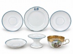PORCELANAS, lote com seis (6) peças confeccionadas em porcelana na tonalidade branca, sendo: A) 5 peças c/ borda filetada nas cores azul e dourado: 1 prato para sobremesa monogramado LD, medindo 18,5cm, fios de cabelo na borda, 2 pires para chá com fio de cabelo na borda, medindo 16cm, 1 pires para café com fios de cabelo, medindo 10,5cm e 1 porta aliança com borda com fio de cabelo e falhas na pintura e 1 xícara para chá sem pires com pintura de ferrovia em policromia, espessa faixa em ouro com elementos vegetalistas,  medindo 5x11x8,5cm. Peças apresentam leves avarias, vide foto.