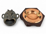 BRONZE e METAL COBREADO, lote com duas (2) peças, sendo: A) 1 cinzeiro ou incensário representando máscara teatral greco-romana em bronze, medindo 9x9cm e B) 1 cinzeiro em metal cobreado com inscrição PORTUGAL, apoiada sobre base sextavada em madeira escura, medindo 11x13cm.