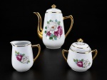 PORCELANA RAMI -  Um (1) conjunto para café composto por 3 peças em porcelana branca vitrificada, sendo um bule , med : 19 cm , uma leiteira , med : 10 cm  e um açucareiro , medida : 11 cm ,  apresentando delicada decoração floral policromada em tons de rosa, branco e verde, e vasta douração , bicado na parte interna da tampa .