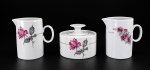 PORCELANA RENNER - Um (1) conjunto de 3 peças em porcelana branca vitrificada, composto por 2 leiteiras e 1 açucareiro com tampa, apresentando decoração floral policromada em tons de rosa e cinza, com delicados frisos dourados. Medida das leiteiras : 10 cm , medida do açucareiro : 8 x 10 cm