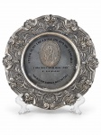 ESTANHO, um (1) prato comemorativo de premiação equestre, em estanho, com rica ornamentação em relevo ao gosto barroco, apresentando motivos florais, concheados e volutas. Medalhão central com figura de cavaleiro e inscrições Federação Equestre do Rio de Janeiro  Copa dos Cavaleiros 1998  1º Lugar  Sociedade Hípica Brasileira, medindo 24cm.