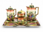 PORCELANA -  Conjunto para café, composto por cinco (5) peças, sendo um (1) bule , med: 18 cm , uma (1) leiteira , med : 12 cm  , um (1) açucareiro , med : 11 cm , uma (1) xícara acompanhada de seu respectivo pires , med : 6 cm e uma (1) bandeja retangular, medida : 30 x 19 cm . Confeccionadas em porcelana branca vitrificada, com rica decoração policromada representando cenas galantes com figuras em trajes de época. Peças com delicados relevos, alças geométricas e detalhes em douração nas bordas, pés e acabamentos. Pequenas falhas na douração .