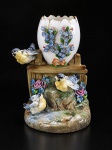 PORCELANA EUROPEIA, uma (1) floreira confeccionada em porcelana na tonalidade branca, bojo no feitio de ovo quebrado, decorado por flores e folhagens em relevo, ladeado por pássaros, apoiados sobre estrutura imitando madeira, apresenta colado e pequenos bicados, medindo 11x9x8cm.