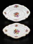 PORCELANA MAUÁ, duas (2) travessas ovais confeccionados em porcelana na tonalidade branca, decorada por flores e folhagens em policromia, bordas onduladas filetadas com caneluras em ouro, falhas na douração, medindo 30x21,5cm e 24x17cm;