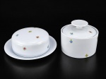 PORCELANAS, duas (2) peças, sendo: A) 1 manteigueira, medindo 6x17,5cm e B) RENNER, 1 açucareiro, medindo 9x11,5cm, confeccionadas em porcelana na tonalidade branca, decorada por flores e folhagens em policromia, tampas dos bules com pega no feitio de disco. Manteigueira sem marcação no fundo.