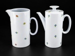 PORCELANAS, duas (2) peças, sendo: A) 1 bule para café, medindo 18,5x16x8cm e B) 1 leiteira, medindo 17x14,5x9cm, confeccionadas em porcelana na tonalidade branca, decorada por flores e folhagens em policromia, tampa do bule com pega no feitio de disco.