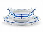 F. LEGRAND & CIE  PORCELANA FRANCESA,  Uma (1) molheira em porcelana branca, de formato oval, com extremidades elevadas e bordas onduladas com presentoir acoplado ,  decorada com espessas faixas geométricas em azul intenso, dispostas horizontal e verticalmente, entremeadas por delicados filetes amarelos. Medida : 10 x 27 x 16  cm , apresenta bicado .