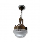 Luminária suspensa de teto pendente. Apresenta estrutura e hastes de sustentação em bronze com detalhes ornamentais em relevo, complementada por cúpula em vidro fosco com ranhuras decorativas na base, medindo 60 cm de altura por 20 cm de diâmetro
