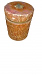 Pote cilíndrico com tampa em pedra esculpida (tons terrosos) com corpo em relevo simulando casca de árvore. Acabamentos em metal dourado e tampa encimada por aplique em formato de folha. Alt.: 12 cm | Diâm.: 9 cm. Marcas do tempo.