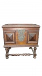 Pequena arca em madeira nobre de estilo Português (Século XVII) entalhada com tampa basculante decorada com marcenaria geométrica em losango, apliques de cantoneiras em metal trabalhado e bordos serrilhados ,fechadura  trabalhado em volutas de gosto barroco, ladeado por dois painéis com almofadas no clássico formato "ponta de diamante". Assenta sobre base com quatro pés torneados em balaústre interligados por travessas em espiral. Belo acabamento e pátina de época.   Estilo Seiscentista (Século XVII) Medidas: 38 x 38 x 31 cm. Bom estado geral, com marcas e pátina naturais do tempo.