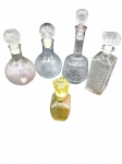 Conjunto composto por 5 garrafas  antigas para  bebidas em vidro moldado e lapidado  Peças de variados formatos com lapidações geométricas em relevo, acompanhadas pelas respetivas tampas.  Medidas: Maior com 32 cm de altura; menor com 17 cm de altura.  Bom estado  com marcas do tempo. Nota: 2 tampas apresentam pequenos quebrados na parte interior.