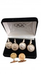 ABOTOADURAS  OLÍMPICOS Conjunto oficial contendo 1 par de abotoaduras em metal dourado e 4 botões de peito de camisa em metal prateado com o emblema dos Anéis Olímpicos em relevo. No estojo original de veludo.
