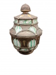 Importante peça decorativa artesanal de origem marroquina apresenta corpo em cerâmica revestido externamente por riquíssima armação em metal  cinzelado e pontilhado à mão. O design é ornamentado com medalhões e faixas decorativas contendo aplicações em esmalte policromado nos tons verde, branco e amarelo, relevos  e motivos geométricos tradicionais. Pega superior moldada em cúpula trabalhada.  Dimensões: 28 cm (altura) x 18 cm (diâmetro máximo).