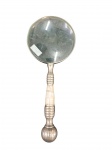 Lupa Decorativa de Secretária em Metal Prateado e MadrepérolaElegante lupa de mão de grande porte, com aro circular em metal prateado e cabo trabalhado contendo anéis torneados e secção central em madrepérola.  Comprimento: 26 cmEstado de conservação: Bom estado geral, apresentando pátina natural de oxidação no metal e lente íntegra.