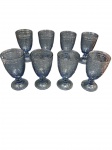 Jogo de 8 Taças em Vidro Trabalhado Azul-Fumé  apresenta ricos relevos decorativos com motivos florais e arabescos, sobre pé redondo trabalhado. Dimensões: 17 cm (altura) x 9 cm (diâmetro) Excelente estado geral.