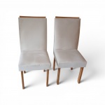 Par de cadeiras de jantar de design contemporâneo  encosto alto e assento inteiramente revestidos em tecido aveludado na cor bege-claro (off-white). pes em madeira clara com acabamento natural, apresentando um detalhe linear em madeira aparente no topo do encosto. , medindo altura total  98 cmAssento: 41 cm de largura x 44 cm de profundidade