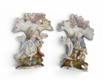Importante Par de Vasos Cornucópia em Porcelana Alemã da Turíngia  Estilo Rococó   em porcelana de pasta dura policromada e guarnecida a ouro, manufatura alemã do final do século XIX. com ricochete de volutas e concheados (rocaille), decoradas com  figuras em vulto pleno dama em atitude de devaneio e um cavaleiro com seu cão de caça. Pintura floral e detalhes indumentários inteiramente executados à mão. Na base de ambas as peças, apresenta numeração de molde "120" e marca de artesão "U" incisas na massa úmida. Alemanha, c. 1900.  Dimensões: 35 x 28 cm  Base: 17 x 16 cm.