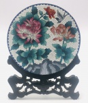 China / Beijing Cloisonné. Belo prato decorativo em branco em autêntico Beijing Cloisonné, que é associado ao luxo imperial. Tem valor artístico e histórico. Sobre o corpo branco, são soldados pequenos cloisons que formam o design. Os cloisons são preenchidos com pigmentos de esmalte. Então, o prato é queimado e polido. São necessárias várias etapas de queima e polimento. O prato é decorado detalhadamente com grandes flores de crisântemos rosa, vermelho e salmão; folhagens em tons de verde azulado e um pássaro voando. Parte inferior: rochas. Cena de celebração da natureza. São visíveis as tiras de cobre que formam os cloisons e percebe-se o relevo. Lindo suporte de madeira, bem entalhado. No inverso apresenta uma textura enrugada, imperfeições comuns do forno e um sinal dos métodos tradicionais de fabricação de Beijing Cloisonné. Durante o processo de queima, a prioridade é a frente do prato, o acabamento do verso é feito posteriormente. É uma característica marcante do processo artesanal, e não um defeito.  Século XX.  Excelente estado de conservação. Diâmetro do Prato 26 cm. Altura com suporte 37 cm.