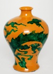 China | Jingdezhen | Amarelo Imperial | Meados do Séc. XX (c. 1950-1980) Raro e impressionante vaso em forma de Meiping (), produzido em porcelana de pasta dura com esmalte Amarelo Imperial. O design apresenta dois poderosos Dragões Celestiais dominando o céu, disputando a Pérola Flamejante entre nuvens. Os elementos decorativos  dragões, nuvens e pérolas  foram finamente incisos (cinzelados) na massa e destacados com esmalte verde sobre o fundo amarelo, uma técnica que revive a combinação cromática historicamente exclusiva da Realeza. Um detalhe excepcional desta peça é a oxidação natural do esmalte amarelo ao longo das décadas; a parte inferior do vaso adquiriu um tom dourado acobreado (pátina de envelhecimento). A técnica de incisão profunda permite que o esmalte verde destaque a musculatura e o dinamismo do dragão,  enquanto a pátina na base atesta a passagem do tempo sobre a porcelana de pasta dura. Este fenômeno é raro, atingindo apenas peças com composições minerais específicas, sendo altamente valorizado por colecionadores por conferir singularidade à obra , embora seja passível de  remoção. Medindo altura 28 cm  x 21 cm diâmetro