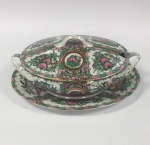 China, Cantão - Porcelana Mandarim com Flor e Pássaro. Porcelana Rose Canton. Ricamente decorada com ouro, rosa, verde, rouge de fer. Marca Honorífica de Reinado QianLong. Terrina com presentoir de porcelana chinesa de pasta dura. Formato Oval. Famille rose, pintura overglaze. Painéis decorados com medalhões rosas, volutas, borboletas e insetos, flores e pássaros. Canton (Guangzhou), onde eram permitidos os estrangeiros a comprar porcelana na China. A Porcelana Kwon-glaze nasce do intercâmbio cultural Ocidente com a China. Presentoir - 32 x 23 cm. Altura total 15 cm. Excelente estado de conservação.