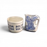 Conjunto composto por duas importantes peças da cerâmica artística nacional decoradas em azul e branco: 1) Cachepot Corcovado Pedreira  Formato cilíndrico com tradicional decoração em relevo recortado e filetes concêntricos. Mede 16 x 18 cm e Jarrinha Luiz Salvador  moldada e pintada à mão com os clássicos e minuciosos arabescos florais característicos . Mede 20 x 18 cm,  bom  estado geral, preservando o brilho do vidrado original. Sem bicados ou trincas.