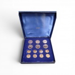 Raro e magnífico lote de 14 botões olímpicos para blazer, manufaturados pela prestigiada Bertoni de Milão. Peças em estado impecável de conservação, ostentando o brilho original do banho a ouro e o esmalte perfeito. Completo, em seu estojo de luxo original da época. Item de extrema raridade no mercado nacional, altamente recomendado para colecionadores de memorabília olímpica.