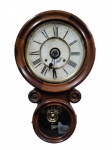 ANSONIA CLOCK CO.  RELÓGIO DE PAREDE AMERICANO ANTIGO (C. 1900)Importante relógio de parede antigo da célebre manufatura americana Ansonia Clock Co., New York. Caixa em madeira nobre torneada e moldurada com volutas laterais e caixa inferior para visualização do pêndulo de latão ornamentado. Mostrador com numeração romana, ponteiros trabalhados e inscrição do fabricante na base.(Peça no estado: necessita de restauro na madeira e reparo no mecanismo do relógio).Acompanha chaves